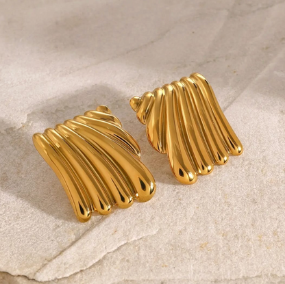 Bold gold plaque earring featuring wavy fluted lines, shown worn on ear.